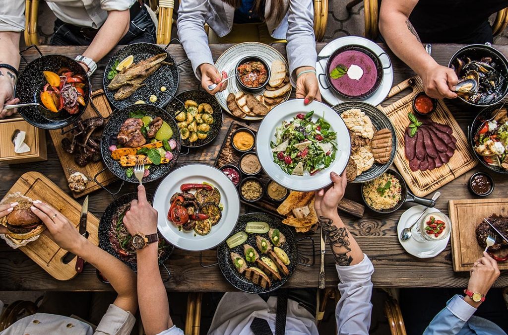 Looking down at a table full of food that a group of people are eating.