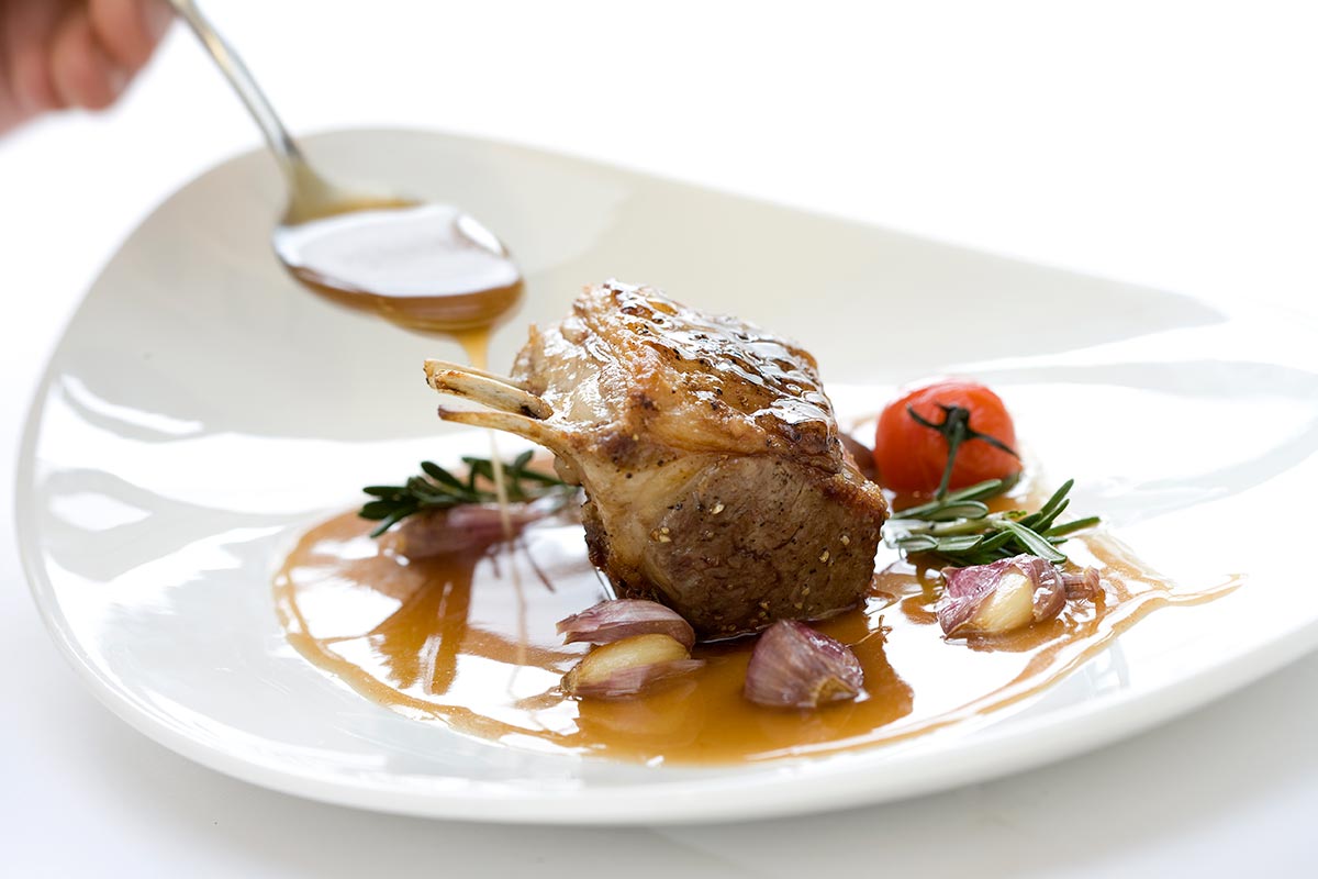 Beef entree with a fine gravy being poured on by a spoon